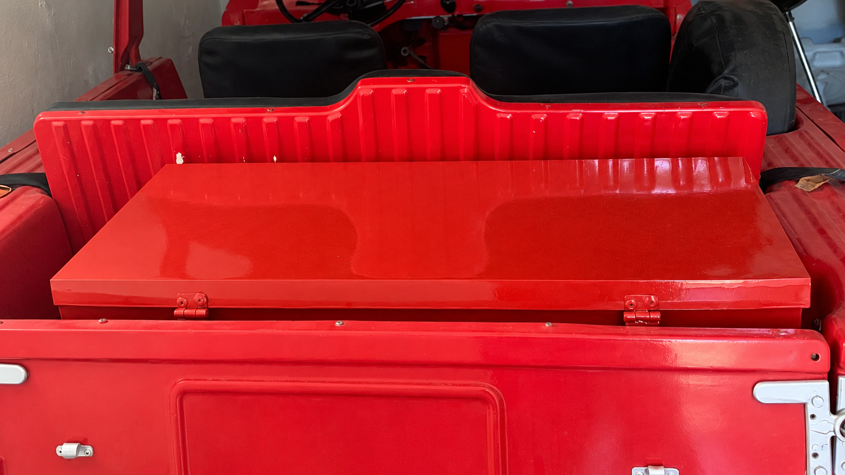 Boîte de rangement rouge avec couvercle dans le coffre d’une Méhari