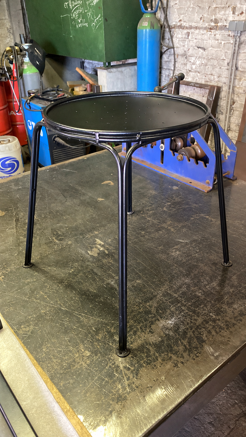 Petite table de jardin en acier noir avec plateau rond à rebord et pieds courbes
